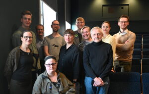 Gruppbild på elva personer som står uppställda bredvid varandra och ler.